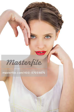 Smiling model in white dress posing touching her temple and her cheek on white background