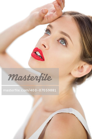 Elegant model in white dress posing with a hand on her forehead on white background