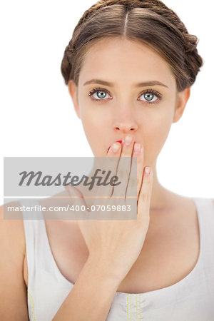 Surprised model in white dress posing covering her mouth on white background