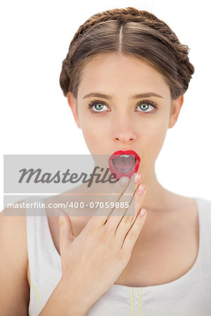 Amazed model in white dress posing covering her mouth on white background