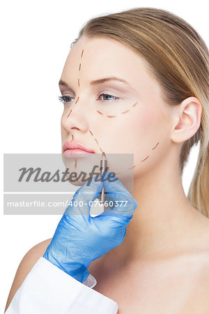Surgeon drawing dotted lines on patients face before surgery