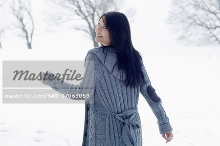 Young female walking in snowy field