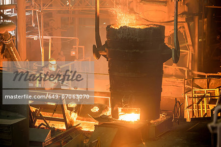 Elevated view of steel worker and molten bucket in steel foundry
