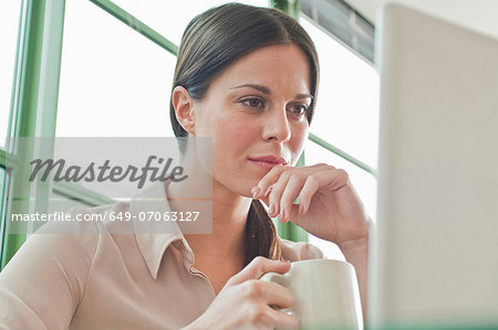 Young female office worker looking at laptop