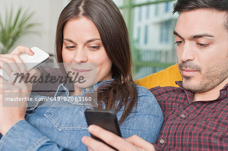 Young couple at home with mobile phones