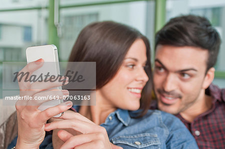 Young couple at home looking at mobile phone