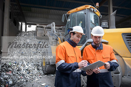 Workers checking clip chart in scrap metal yard