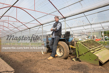 Portrait of organic farmer with tractor in polytunnel Portrait of organic farmer with tractor in polytunnel
