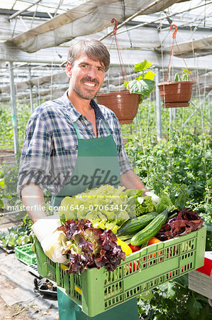 Portrait of organic farmer carrying a tray of fresh produce