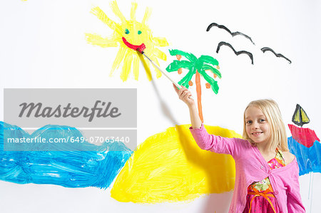 Young girl painting smiling sunshine face on wall