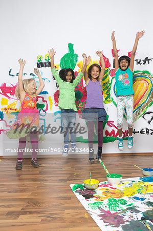 Girls jumping in front of painted wall