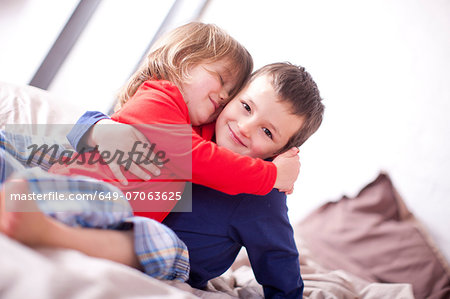 Two young children hugging on bed