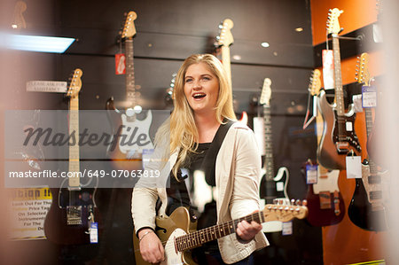 Young female testing guitar in music store