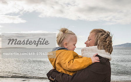 Grandmother and toddler hugging at coast