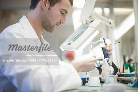 Dental technician using magnifier to repair denture