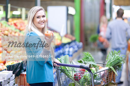 Young woman holding apple in indoor market