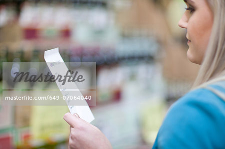 Young woman looking at shopping list in supermarket