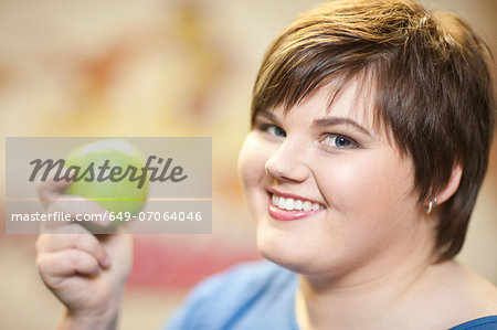 Close up portrait of young woman holding apple