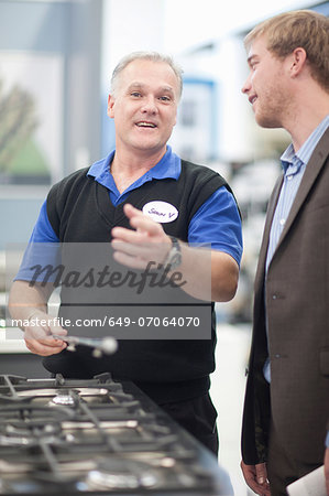 Young man negotiating with salesman in showroom