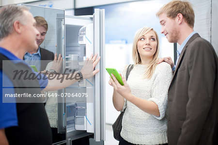 Young couple looking at fridge in showroom