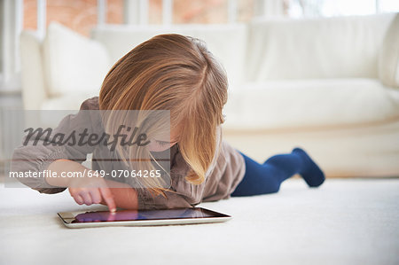 Girl lying on floor using digital tablet
