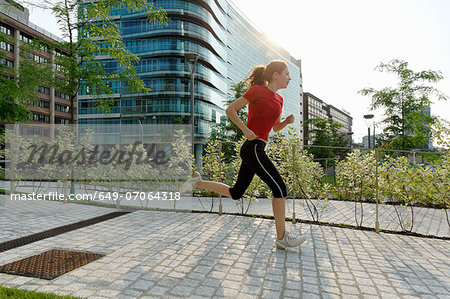 Young woman running past office buildings