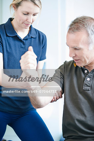 Physiotherapist helping man to do arm exercise