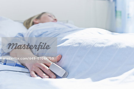 Patient lying on hospital bed with monitor on finger