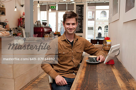 Portrait of young man with coffee and digital tablet in cafe