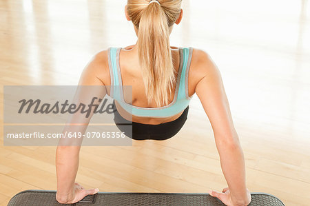 Rear view of woman doing press ups on step