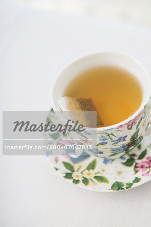 Cup of tea in pretty floral cup and saucer on white background, studio shot