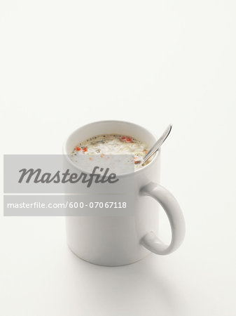Soup and spoon in white mug, on white background, studio shot