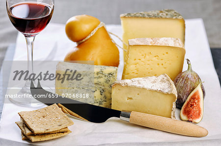 Assorted types of cheese with figs, crackers and a glass of port