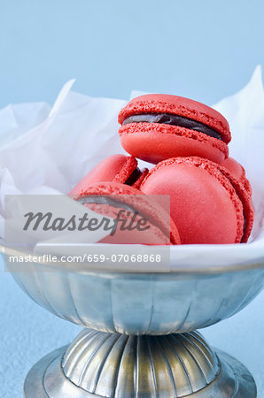 Raspberry macaroons with chocolate filling in a tin dish