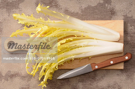 Dandelion leaves on a chopping board with a knife Dandelion leaves on a chopping board with a knife