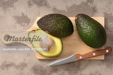 Fresh avocados on a chopping board with a knife Fresh avocados on a chopping board with a knife
