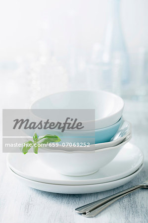 Stacked dinner bowls and plates, drinking glasses and forks Stacked dinner bowls and plates, drinking glasses and forks