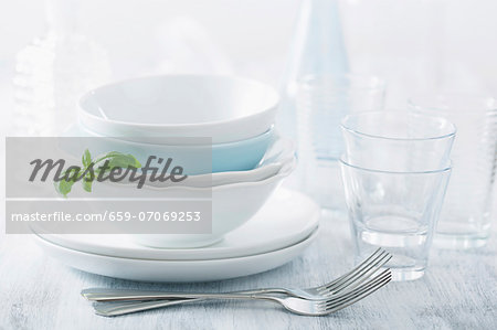 Stacked dinner bowls and plated, drinking glasses and forks Stacked dinner bowls and plated, drinking glasses and forks