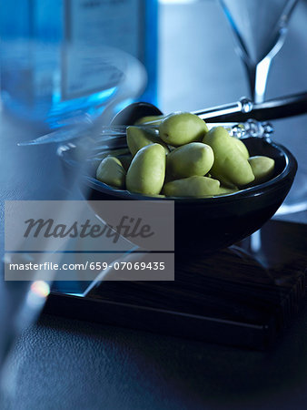 A bowl of green olives between martini glasses A bowl of green olives between martini glasses