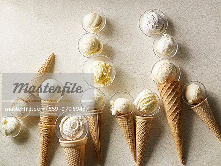 Scoops of vanilla ice cream in wafer cones and glass dishes