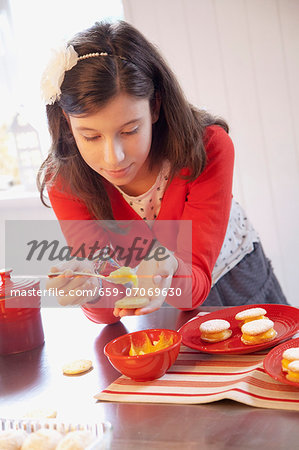 A girl filling biscuits with lemon curd