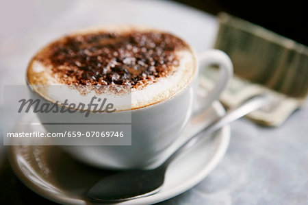 A cup of cappuccino, dollar bills in the background A cup of cappuccino, dollar bills in the background