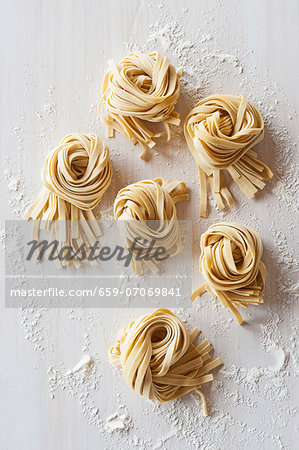 Nests of flat noodles on a floured worktop (view from above)