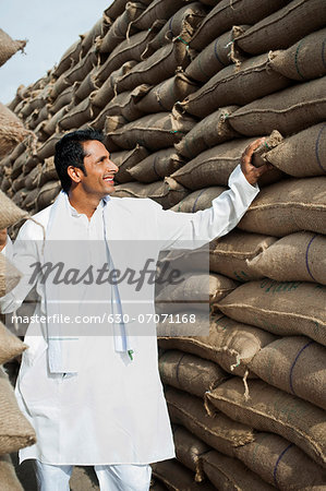Man looking at stacks of wheat sacks in a warehouse, Anaj Mandi, Sohna, Gurgaon, Haryana, India