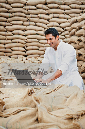 Man using a laptop in a grains market, Anaj Mandi, Sohna, Gurgaon, Haryana, India