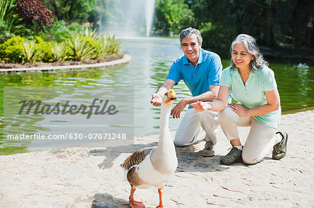 Mature couple calling a duck in a park, Lodi Gardens, New Delhi, India