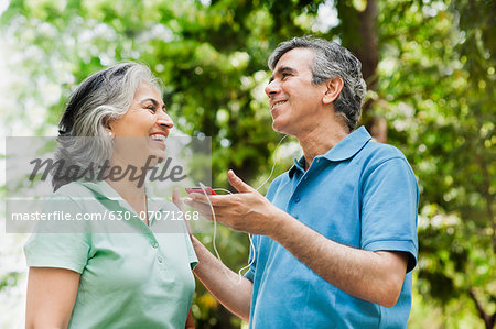 Mature couple listening music with an MP3 player, Lodi Gardens, New Delhi, India