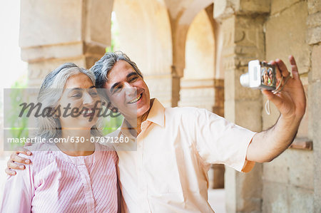 Mature couple taking picture of themselves with a digital camera, Lodi Gardens, New Delhi, India