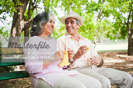 Woman knitting with her husband sitting beside her in a park, Lodi Gardens, New Delhi, India