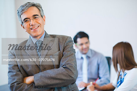 Portrait of a businessman smiling with his colleagues discussing in the background